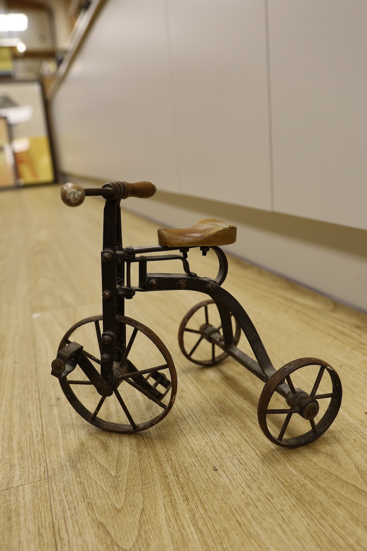 A cast iron toy model of a tricycle, a carved wooden bow, a classical figurative door knocker, a pair of metal cow shoes and two ceramic cistern pulls, bowl 30cm diameter. Condition - fair